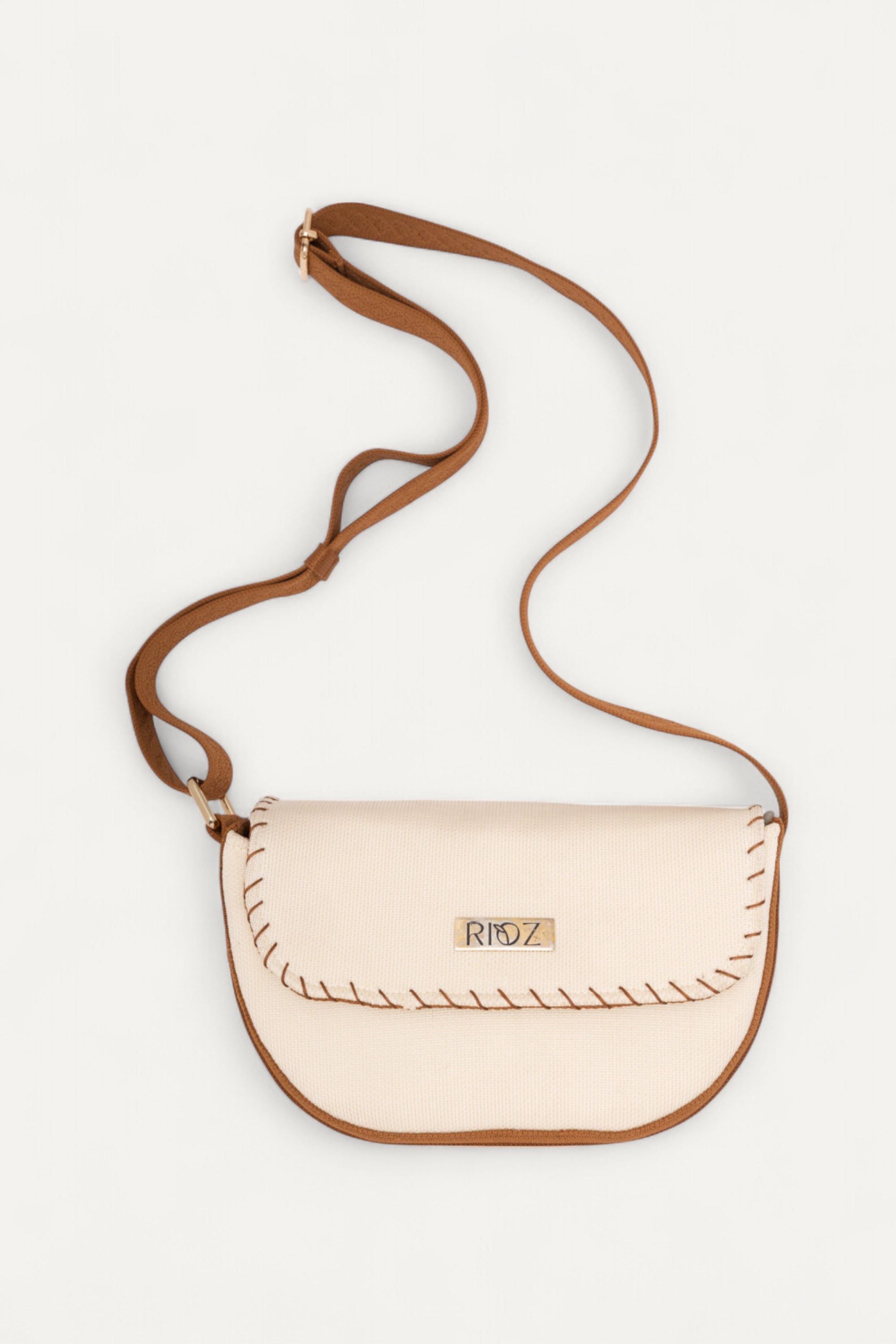 Eco-friendly 9 to 9 Saddle Bag by Rioz with brown crossbody strap and ivory body, handcrafted from sustainable materials; compact, stylish design ideal for everyday essentials and hands-free use.