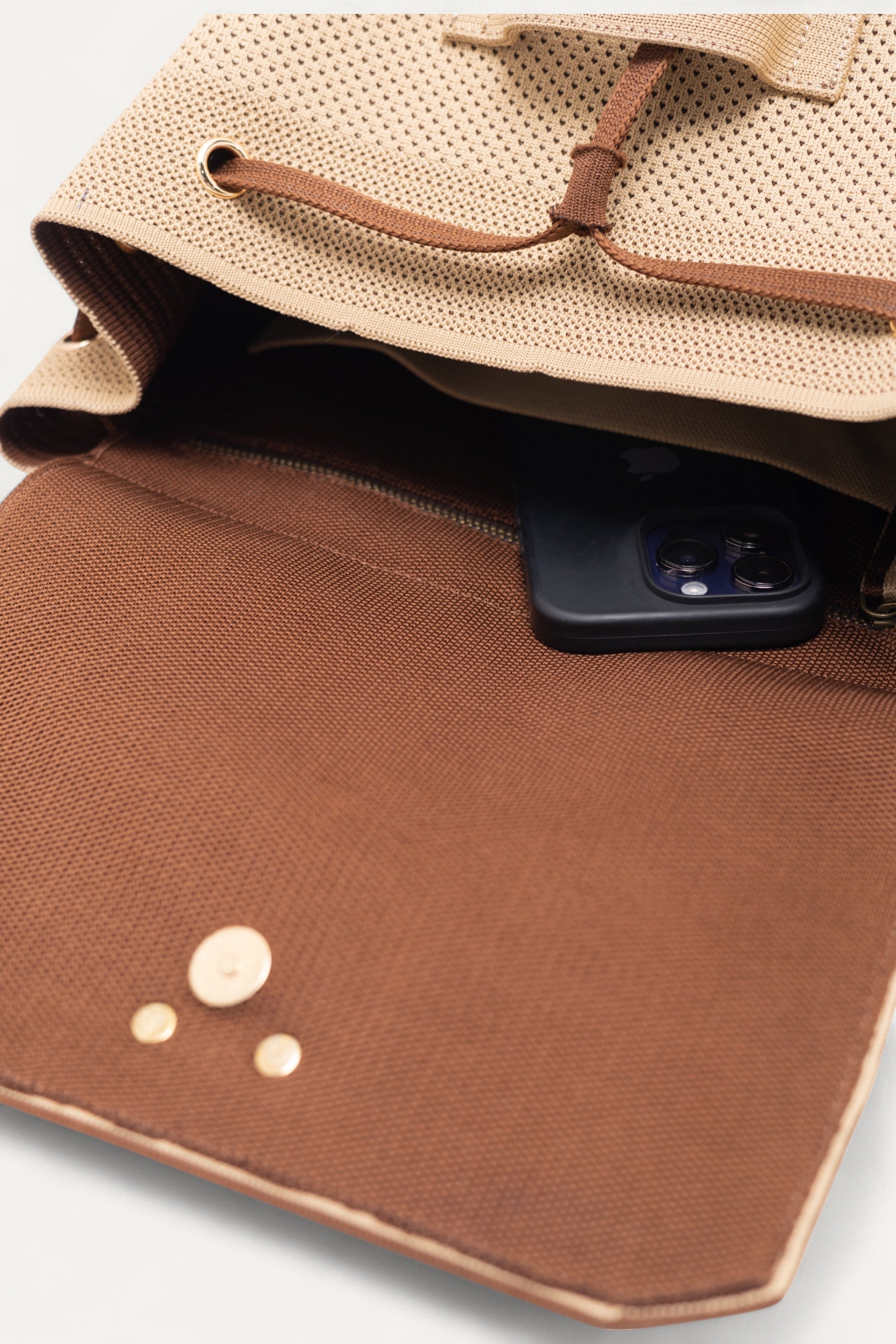 Close-up of the open Rioz backpack showing the interior pocket with a smartphone; eco-friendly backpack made from recycled PET material that is spacious and machine-washable.
