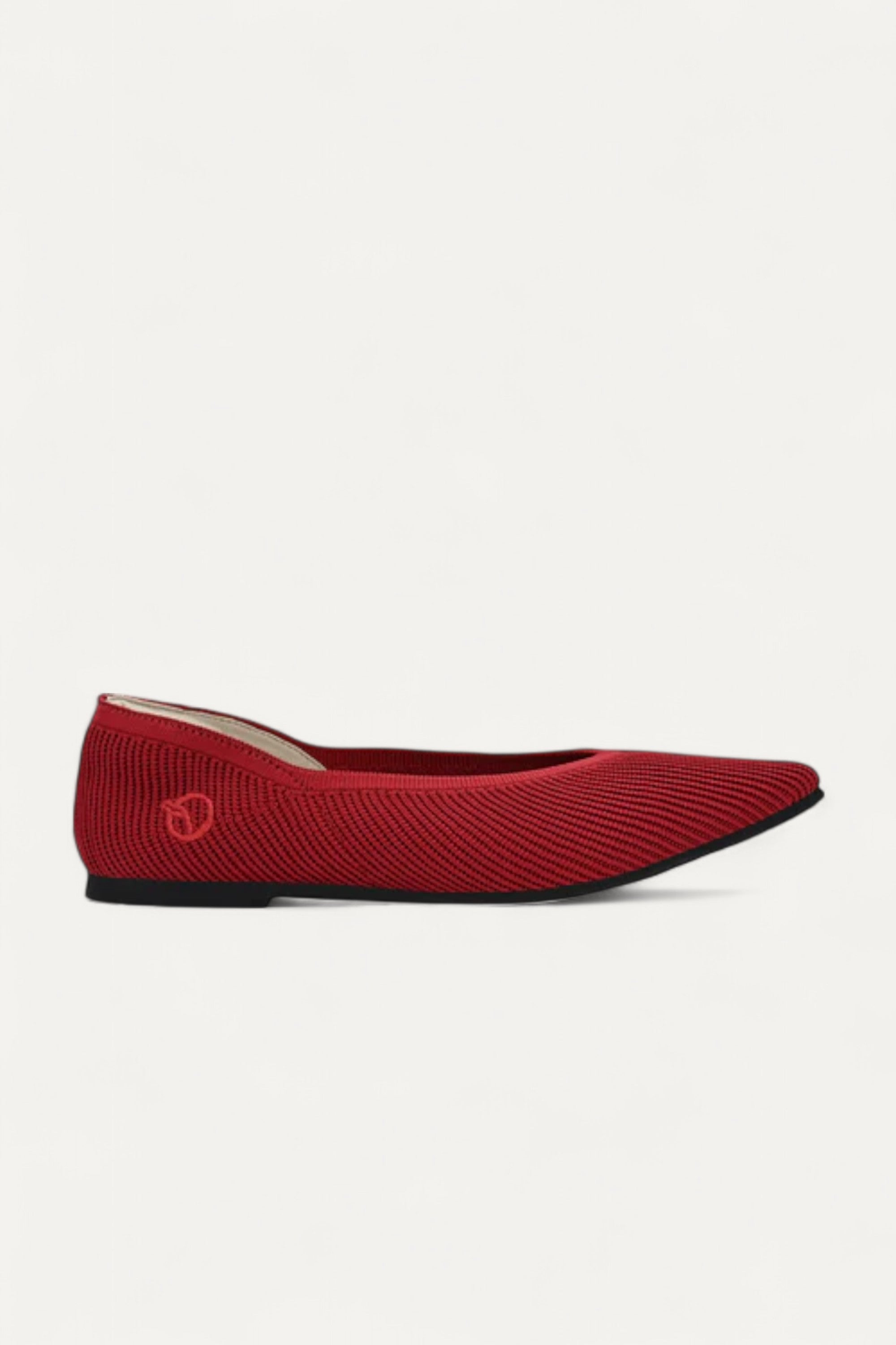 Side view of red pointed-toe ballet flat on light gray background