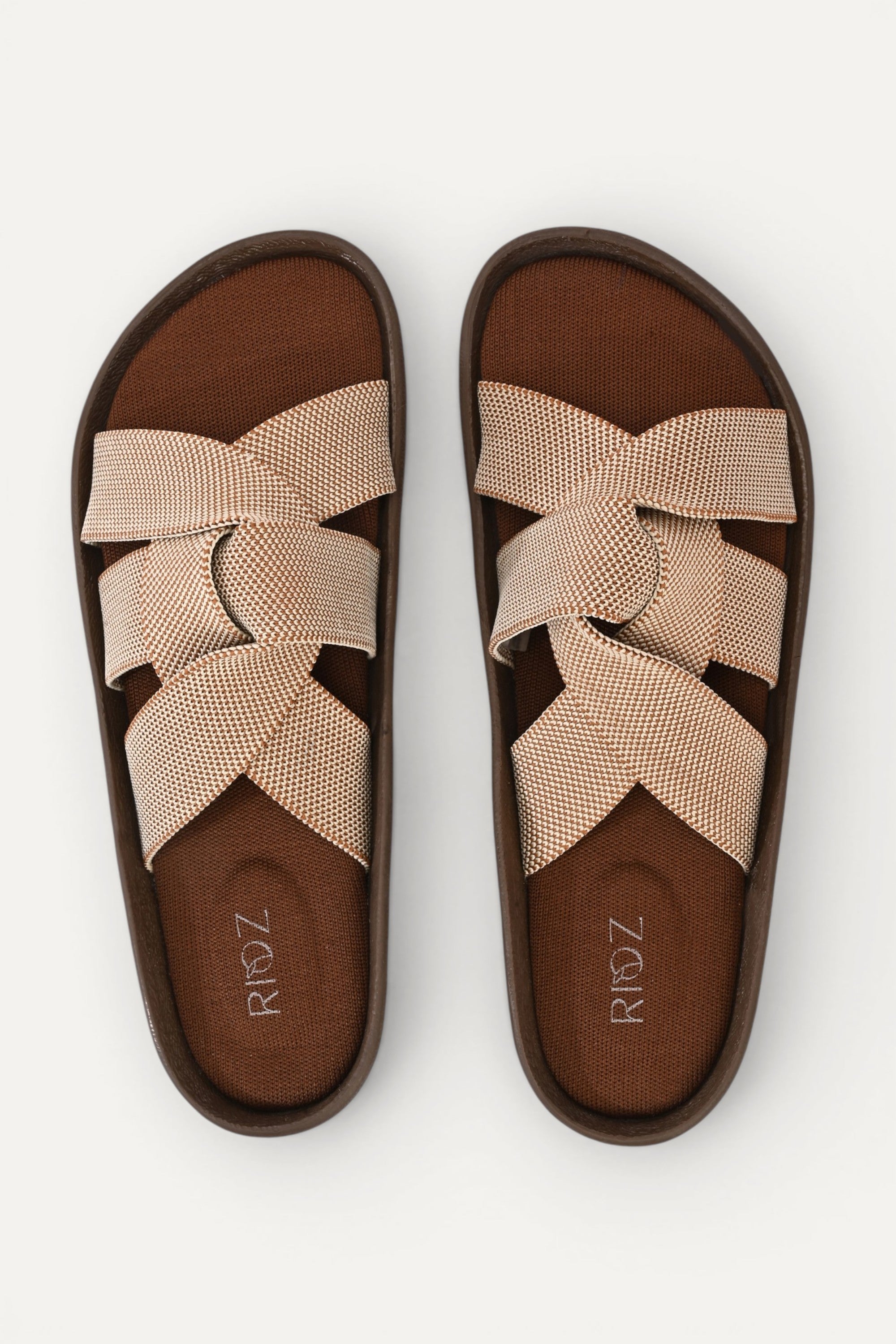 RIOZ eco-friendly slip-on sandals with brown beige woven bow straps, cushioned tan footbed, and brown sole, designed for lightweight everyday comfort and sustainable style.