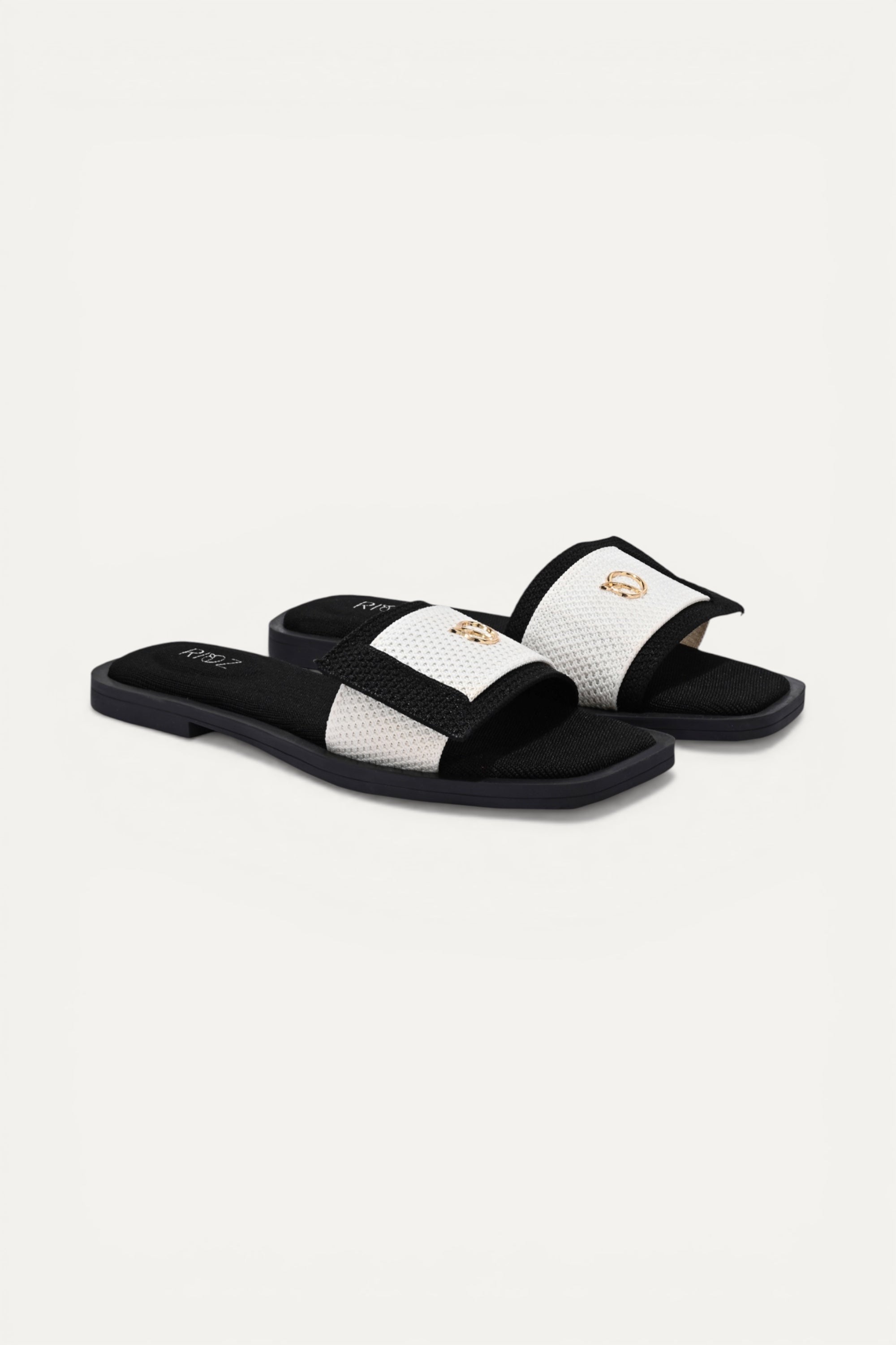 Rioz black and white knit origami slides with gold emblem detail. Asymmetrical design, modern, minimalist.