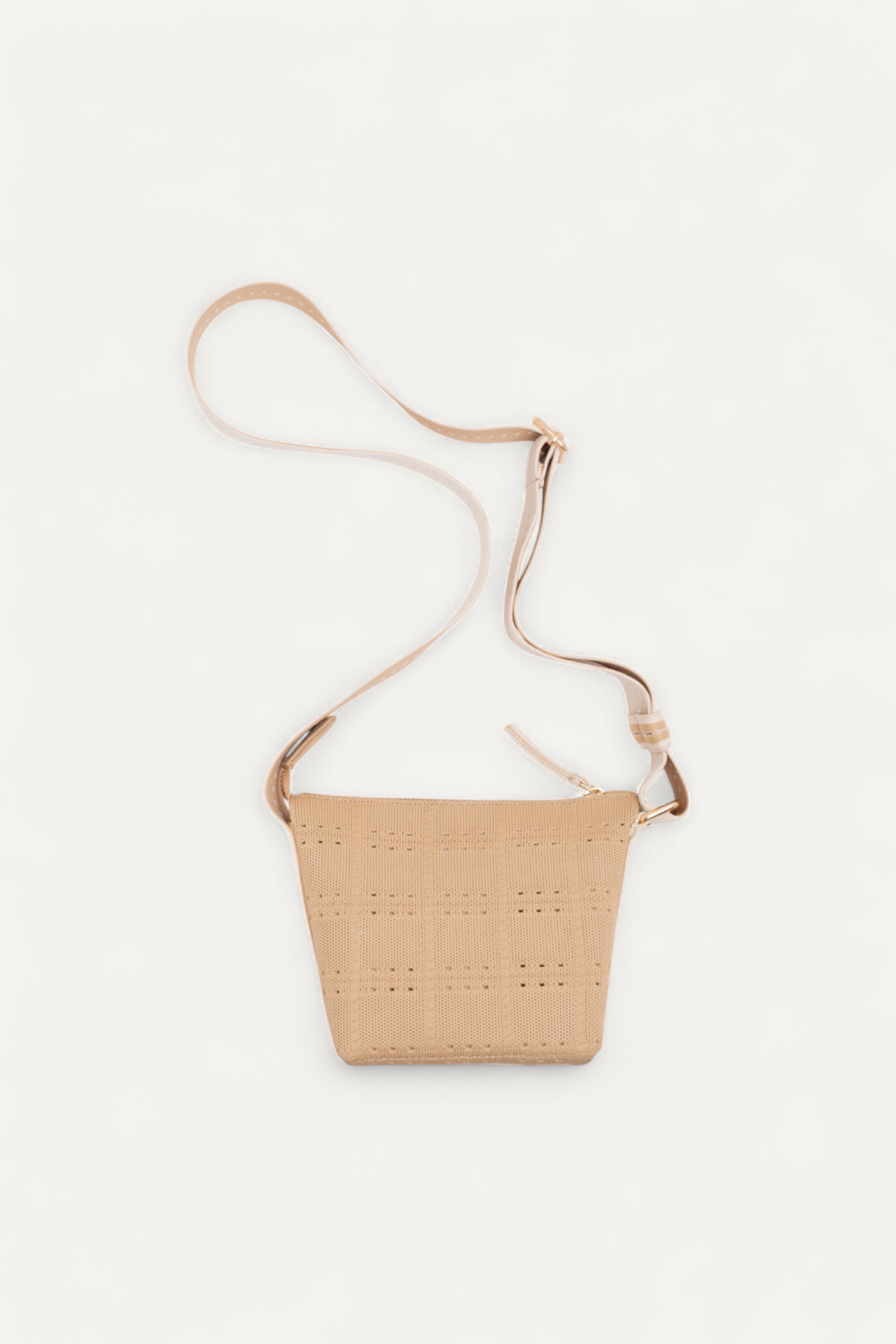 Beige crossbody bag by Rioz with long adjustable strap; perforated woven texture; eco-friendly and compact; displayed on white background.