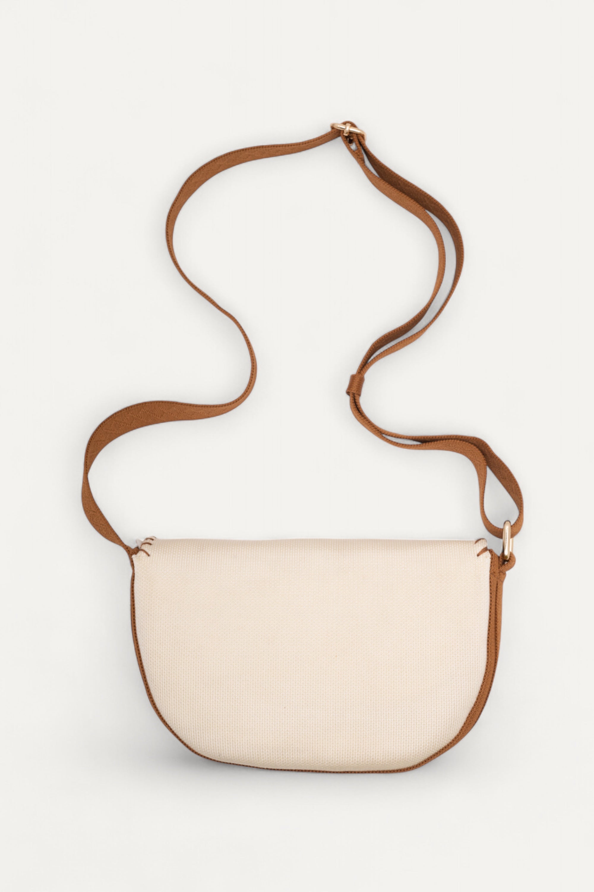 Back view of the 9 to 9 Saddle Bag by Rioz showing its ivory body and long brown crossbody strap; an eco-friendly, compact bag crafted from sustainable materials.