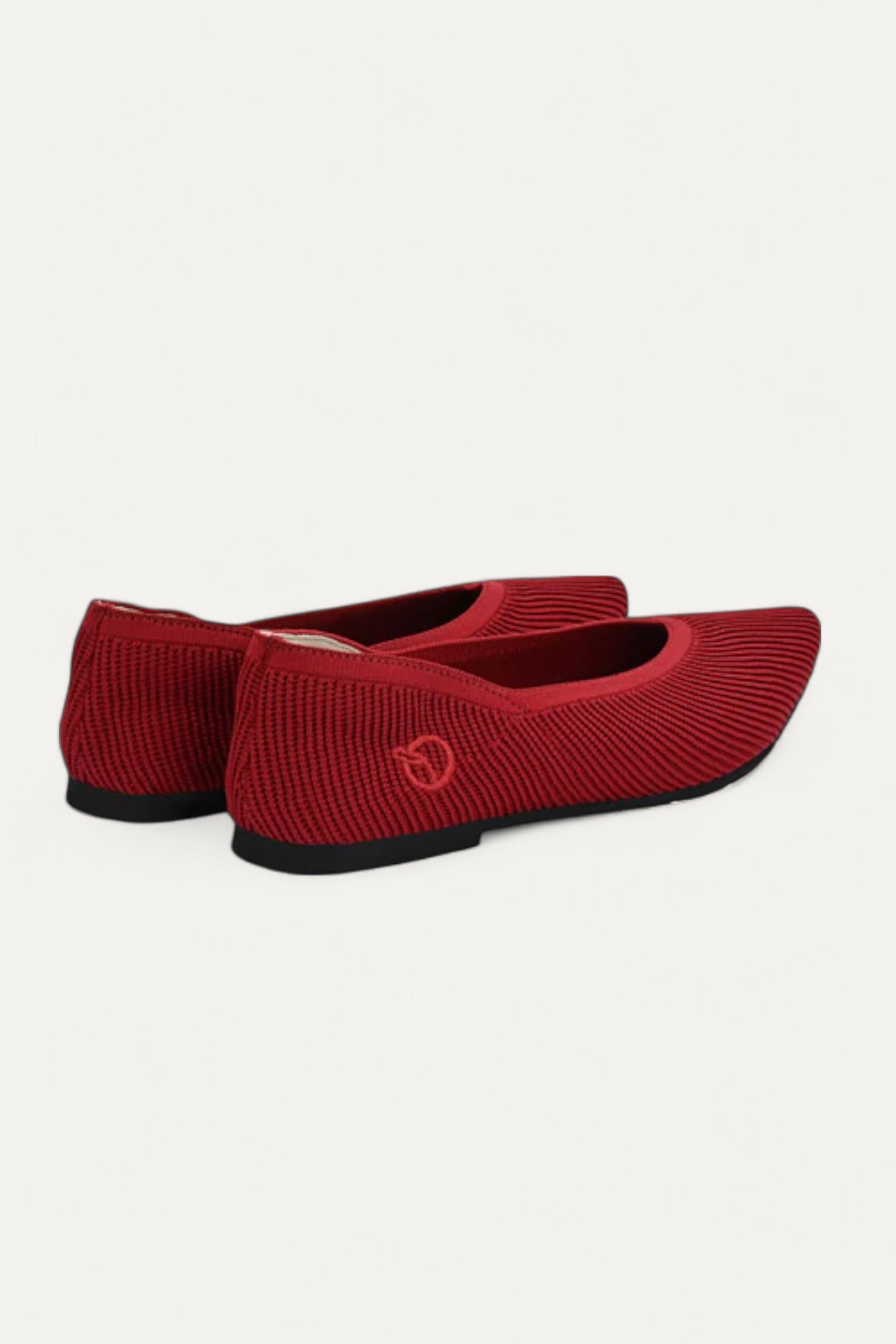 Pair of red pointed-toe ballet flats side by side on white background