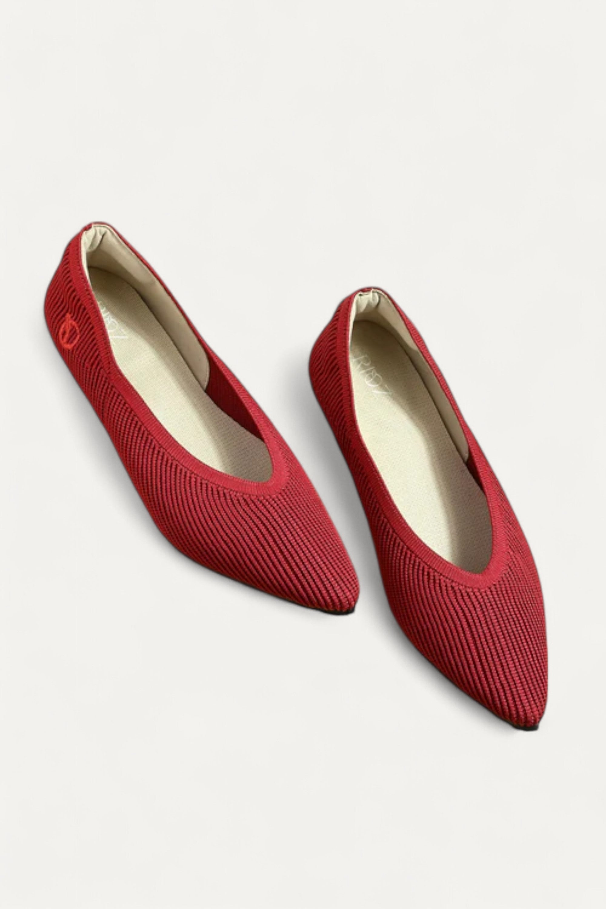 Pair of red pointed-toe ballet flats on light gray background
