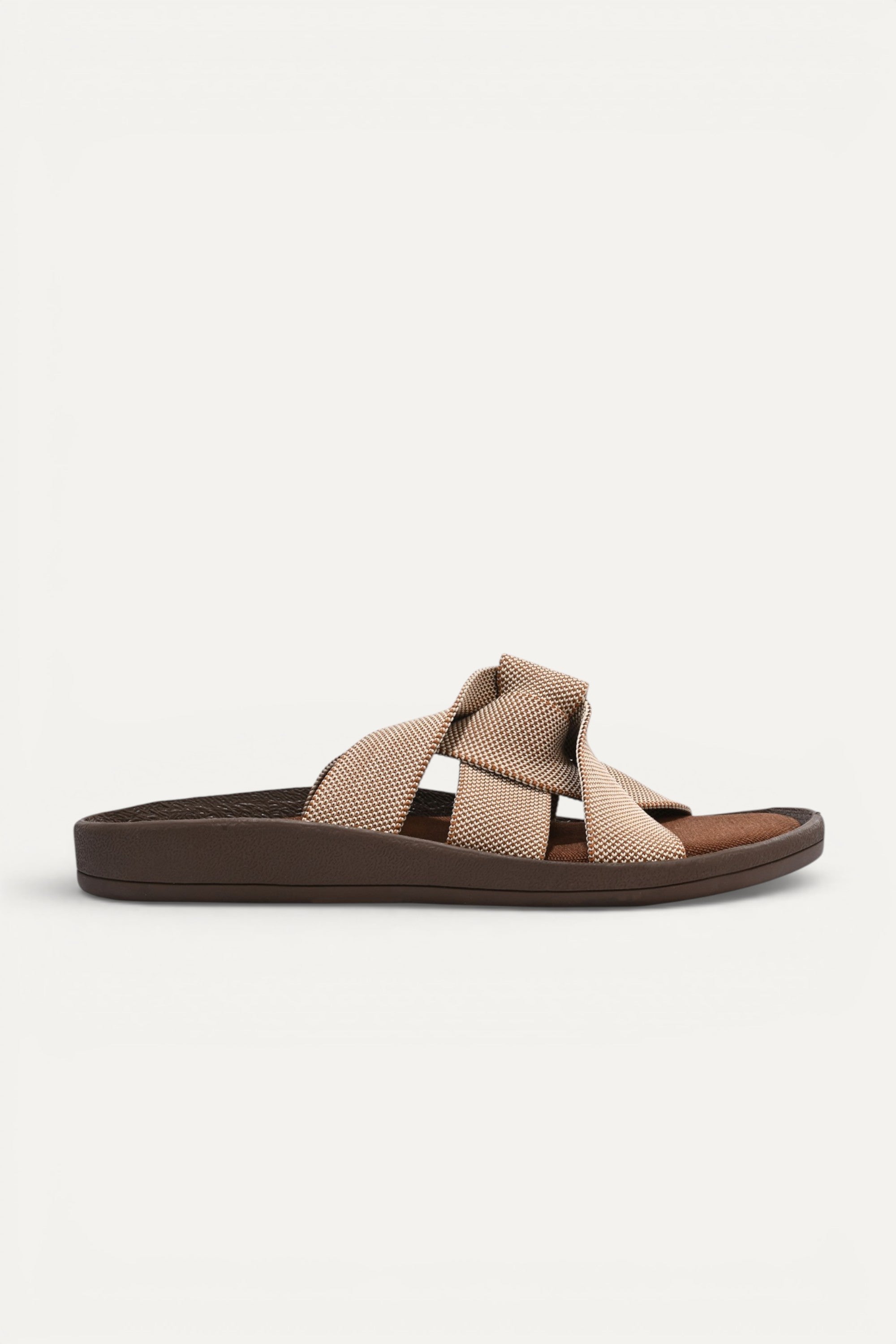 RIOZ eco-friendly slip-on sandals with brown beige woven bow straps, cushioned tan footbed, and brown sole, designed for lightweight everyday comfort and sustainable style.
