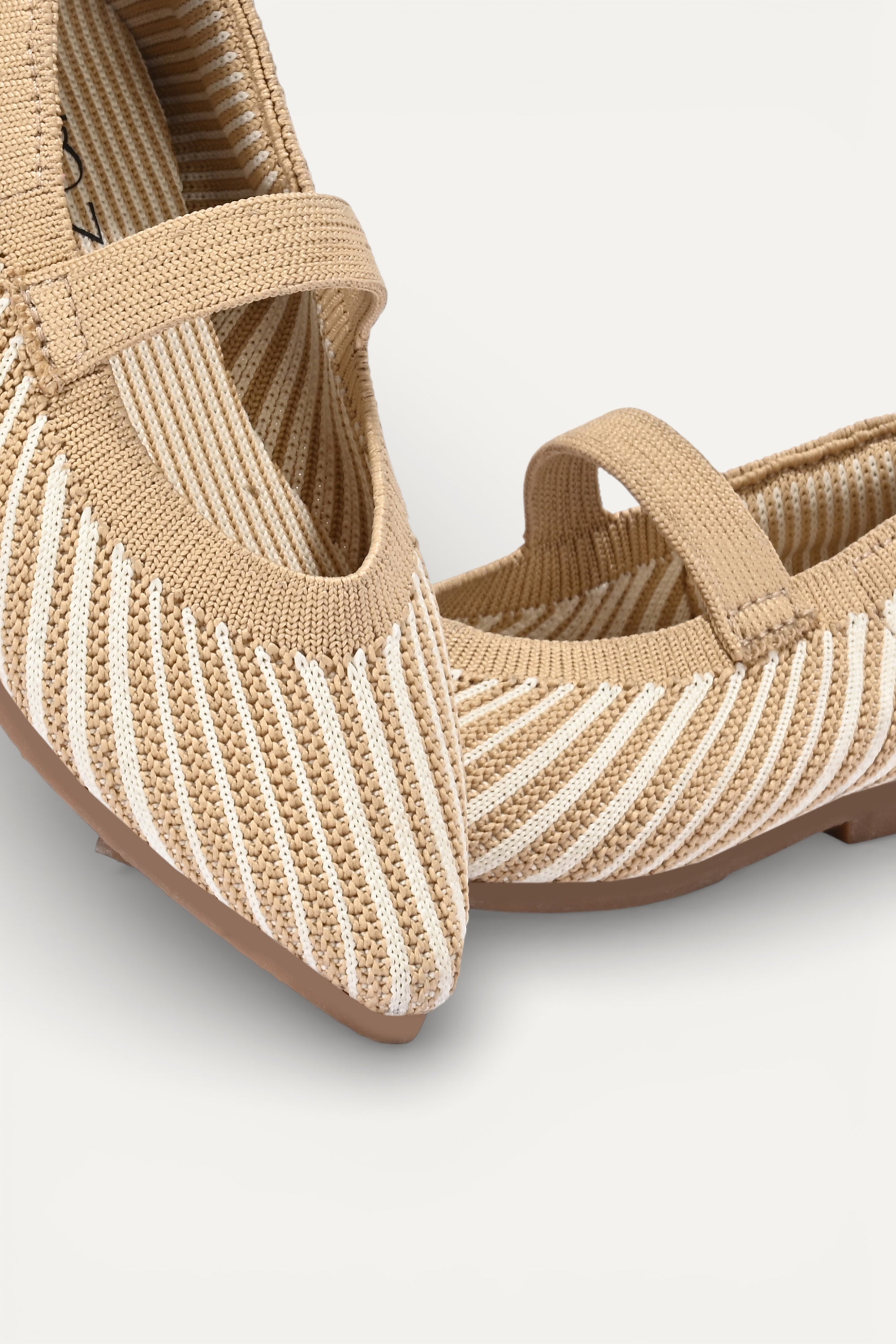 Beige and cream knit Mary Jane flats with strap, breathable striped pattern upper, lightweight flexible sole, comfortable everyday footwear for kids.
