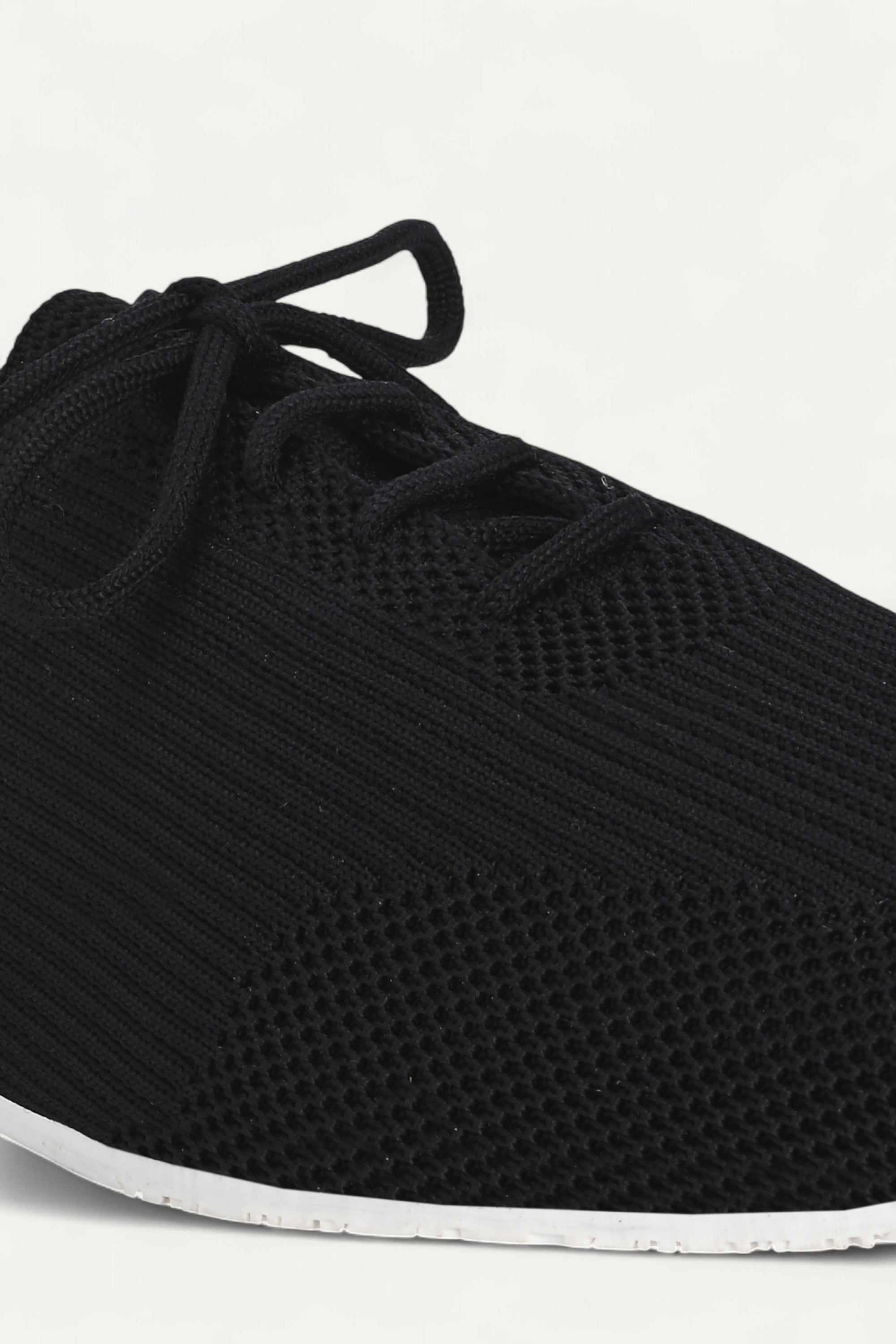 Rioz black knitted lace-up shoes with breathable mesh design, lightweight casual sneakers for women with flexible sole, angled view on neutral background.