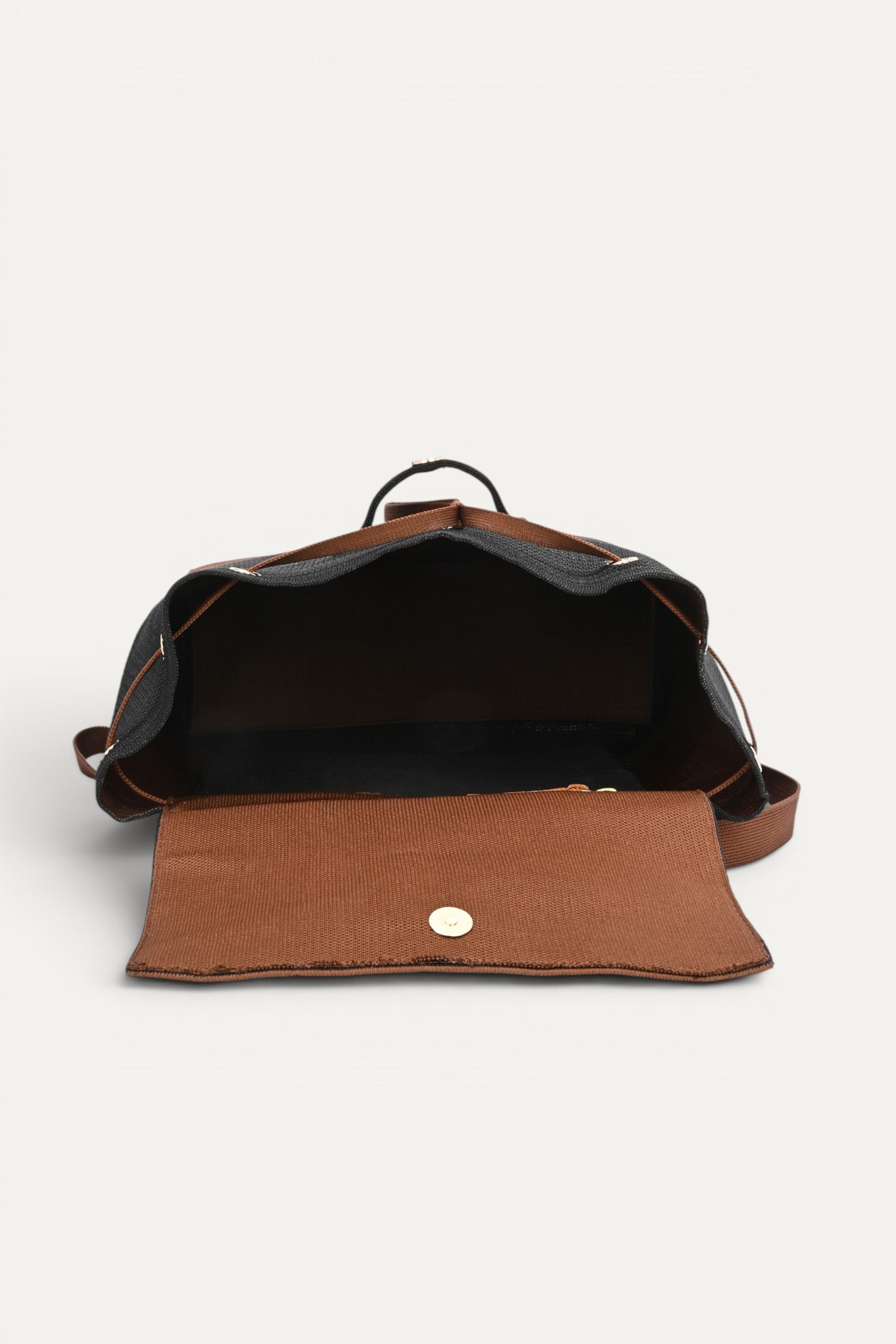 Eco-friendly black woven backpack with brown trim, flap closure and drawstring detail, top handle and shoulder straps, minimalist sustainable design and made from recycled PET bottles for  for everyday use.