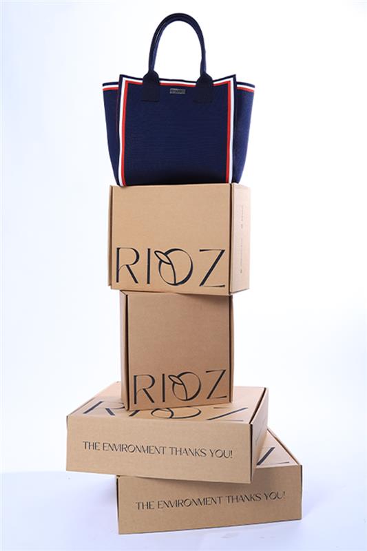 Blue handbag placed on cardboard boxes with 'RIOZ' branding on a white background
