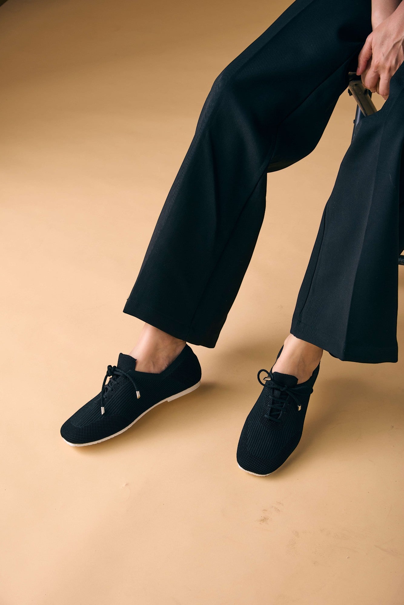 Rioz black knitted lace-up shoes with breathable mesh design, lightweight casual sneakers for women with flexible sole, angled view on neutral background.